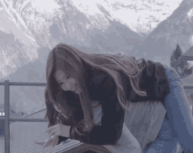 two women are hugging each other in front of a mountain .