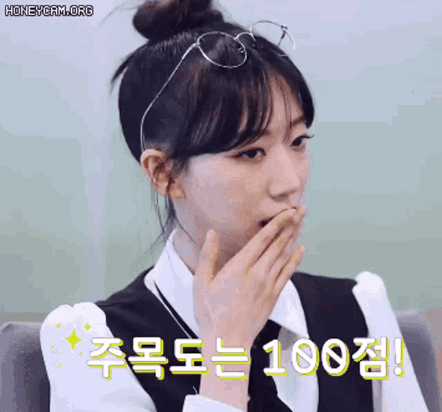 a woman wearing glasses and a bun covering her mouth with her hand and the words honeycam.org in the corner