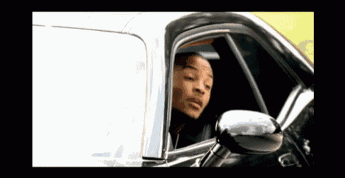 a man is driving a car and looking out of the window