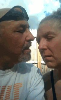 a man and a woman are looking at each other and the man is wearing a hat
