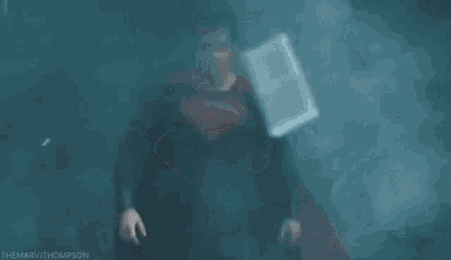a man in a superman costume is walking through a dark room .
