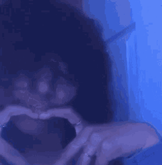 a woman with curly hair is making a funny face in front of a blue wall .