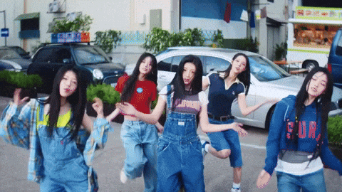 a group of girls are dancing in a parking lot and one of them is wearing a shirt that says surf