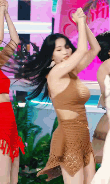 a woman in a brown dress is dancing with her hands in the air .