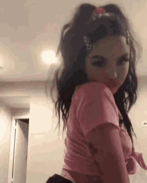 a girl in a pink shirt and black shorts is standing in a room .