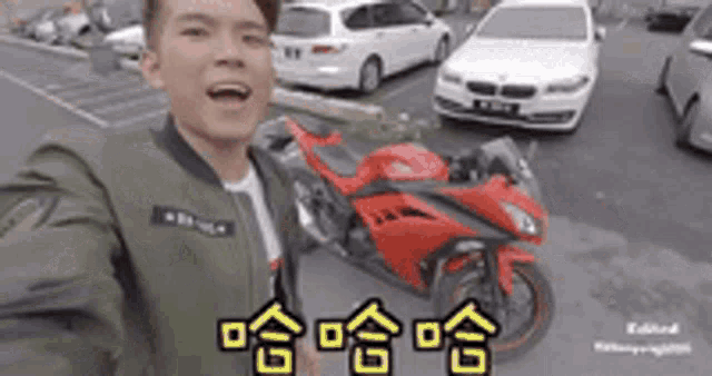 a man is taking a selfie with a red motorcycle in a parking lot .
