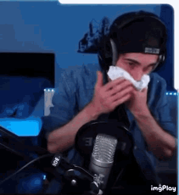 a man wearing headphones is blowing his nose into a napkin .