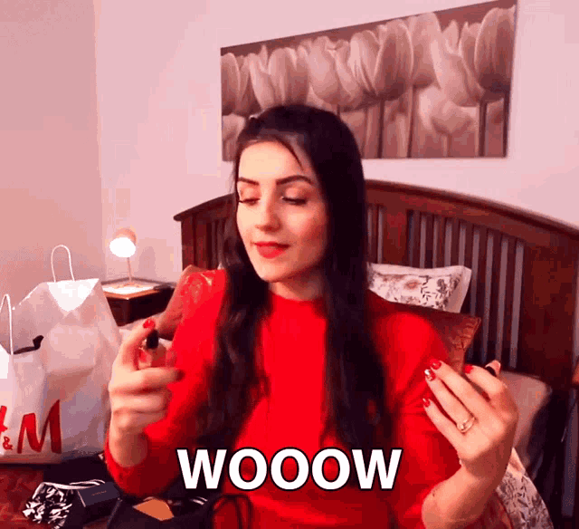 a woman in a red sweater is holding a red object and the word wooow is on the bottom right