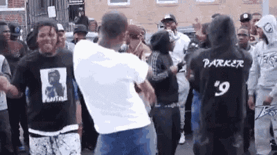 a group of young men are dancing in a street in front of a brick building .