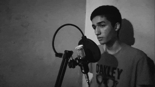 a young man is singing into a microphone and his shirt says oakley