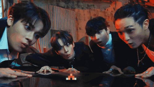 a group of young men standing around a table looking at something .