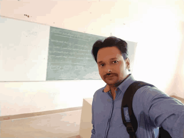 a man taking a selfie in front of a blackboard that says ' mathematics ' on it