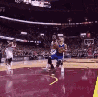 basketball players are playing a game of basketball in a stadium with a crowd watching .