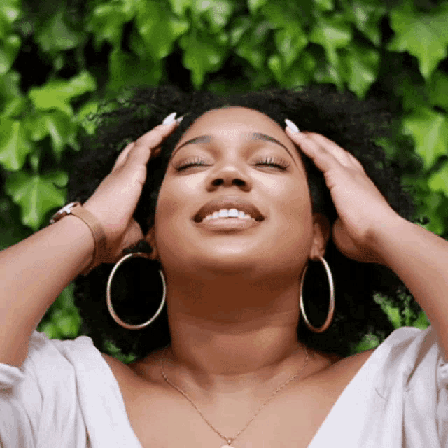 a woman wearing hoop earrings and a necklace is smiling