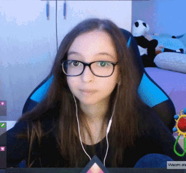 a girl wearing glasses and ear buds is sitting in front of a screen that says wacom on it
