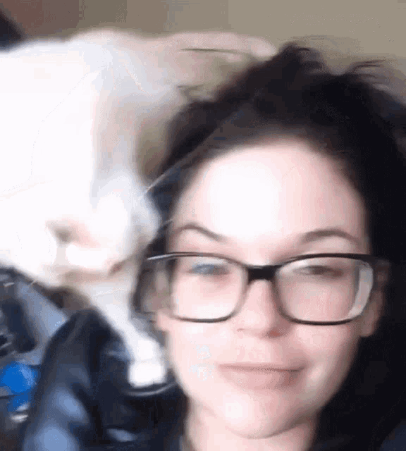 a woman wearing glasses and a cat on her head .