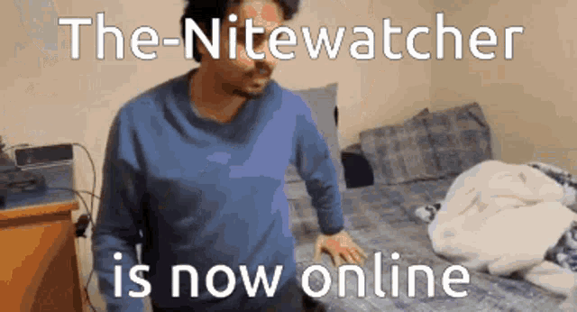 a man in a blue sweater is standing in front of a bed with the words " the nitewatcher is now online " above him