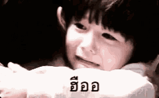 a little girl is laying on a pillow with a foreign language written on it .