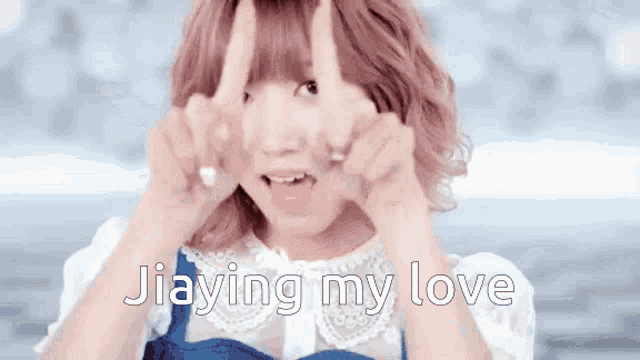 a girl with pink hair is making a peace sign with her hands and the words jiaying my love behind her