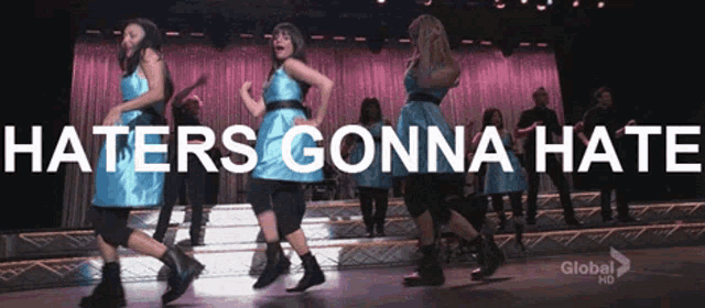 a group of people are dancing on a stage with the words haters gonna hate written above them