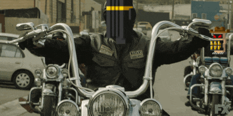 a man on a motorcycle has a patch on his vest that says ' hells angels ' on it