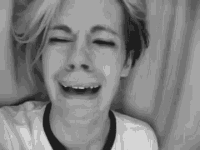 a black and white photo of a young man crying with his eyes closed .