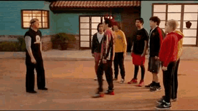 a group of young men are standing in a circle in front of a building .