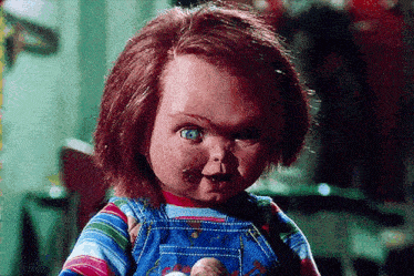 a doll with red hair and blue eyes is holding a stuffed animal and looking at the camera .