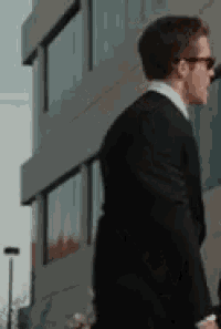 a man in a suit and tie is walking in front of a large building .
