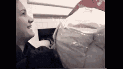 a woman is smiling while holding a bag of food in a black and white photo .
