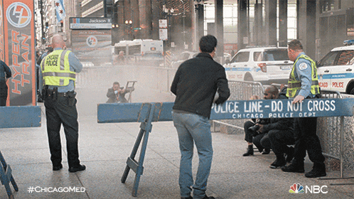a chicago police officer stands in front of a sign that says " police line do not cross "