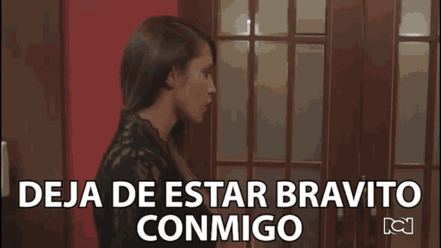 a woman is standing in front of a door with the words deja de estar bravito conmigo written above her