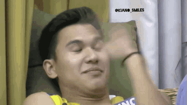 a man is sitting on a couch with his eyes closed and his hand on his forehead .