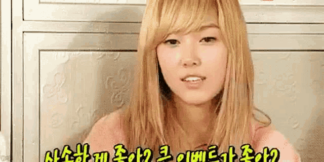 a close up of a woman with blonde hair making a funny face in a pink shirt .