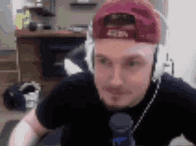 a man wearing headphones and a red hat is looking at the camera .