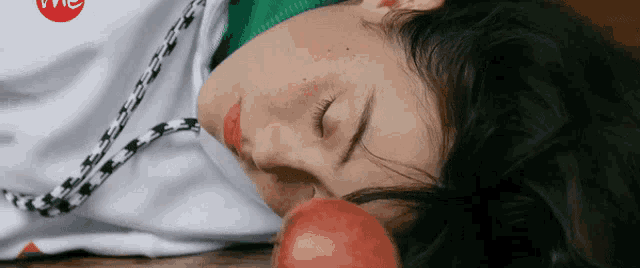 a woman is sleeping on a wooden floor with an apple in her mouth .