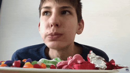 a young boy is looking at a plate of candy with a sticker that says ' candy ' on it