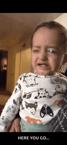 a baby is crying and a person is holding him .