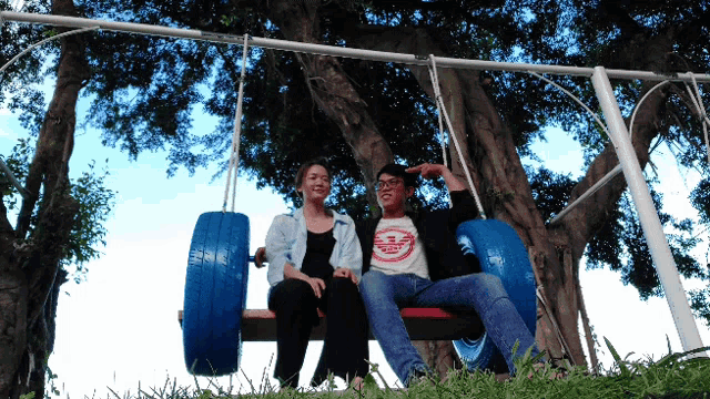 a man wearing an armani shirt sits next to a woman sitting on a tire swing