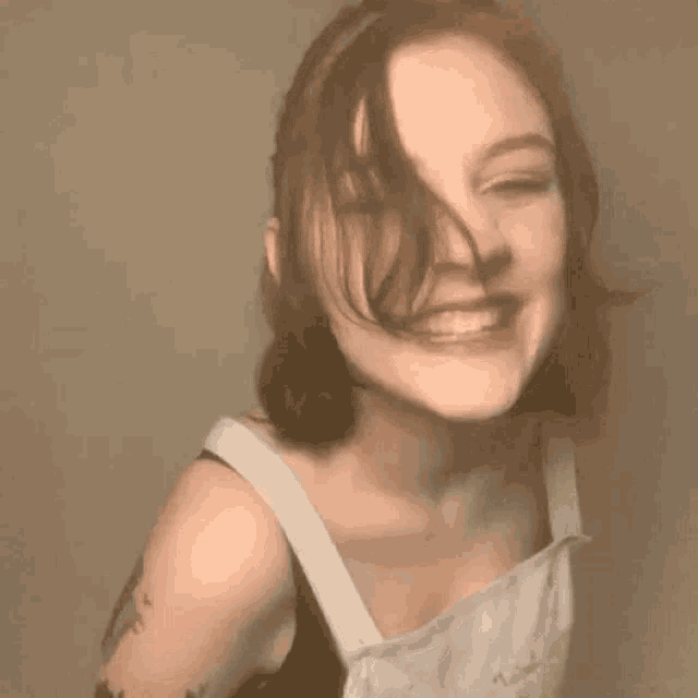 a woman with short hair is smiling for the camera while wearing overalls .