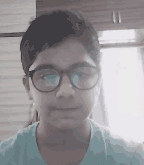 a young boy wearing glasses and a blue shirt smiles for the camera