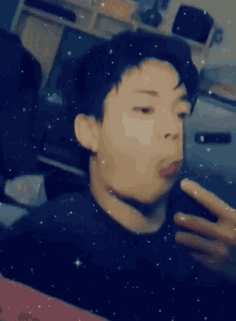 a young man is taking a selfie in front of a mirror with his tongue out .