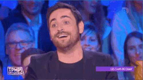 a man with a beard is sitting in front of a crowd of people .