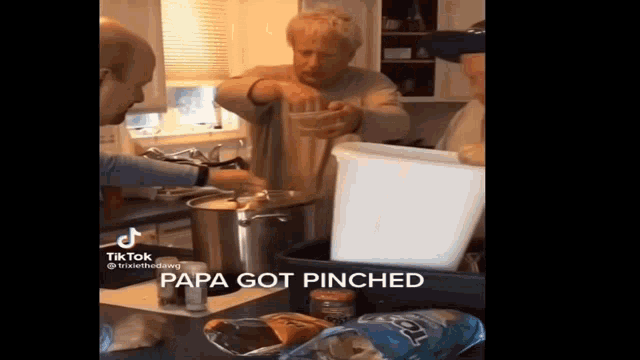 a group of men are cooking in a kitchen and one of them is holding a glass .