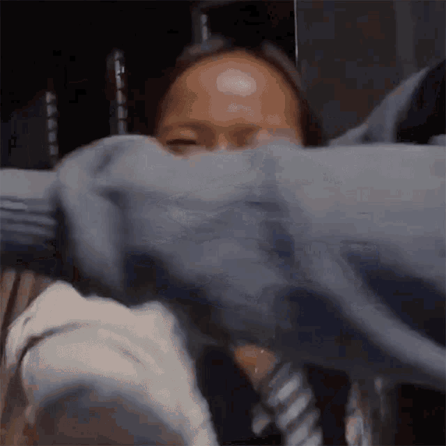 a person is covering a woman 's face with a blue sweater .