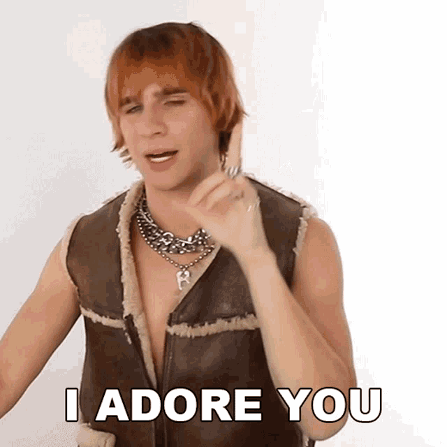 a man with red hair is wearing a brown vest and necklace and says i adore you