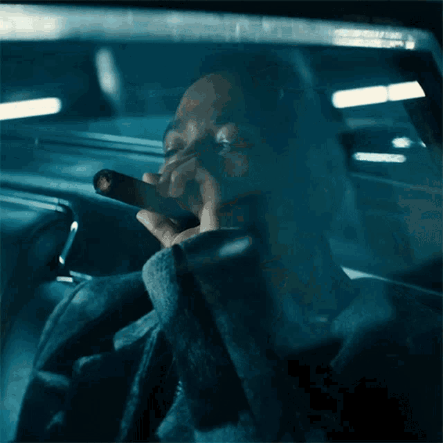 a man smoking a cigarette in a car with his eyes closed