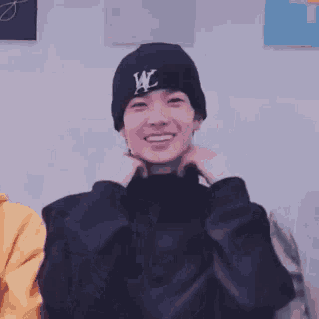 a man wearing a black turtleneck and a black beanie with the letter w on it