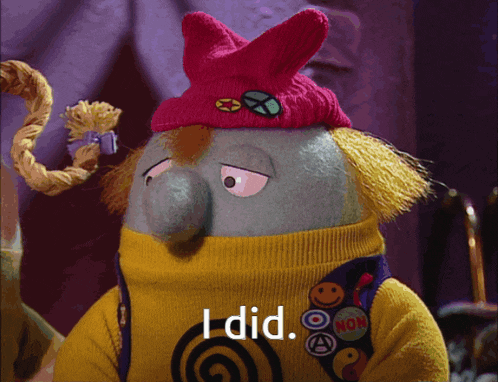 a stuffed animal wearing a yellow sweater and a pink hat with the words i did on it