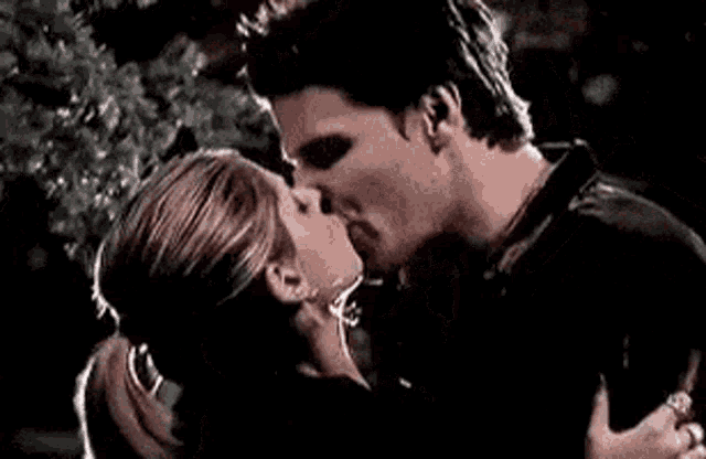 a man and a woman are kissing in the dark .